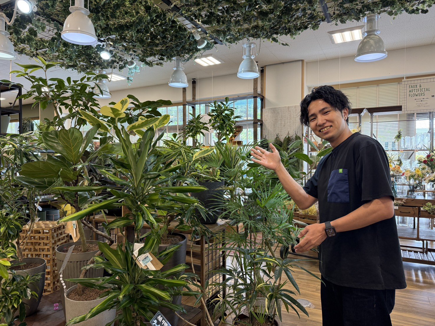 店内に並ぶ大きめのグリーンを案内するスタッフ